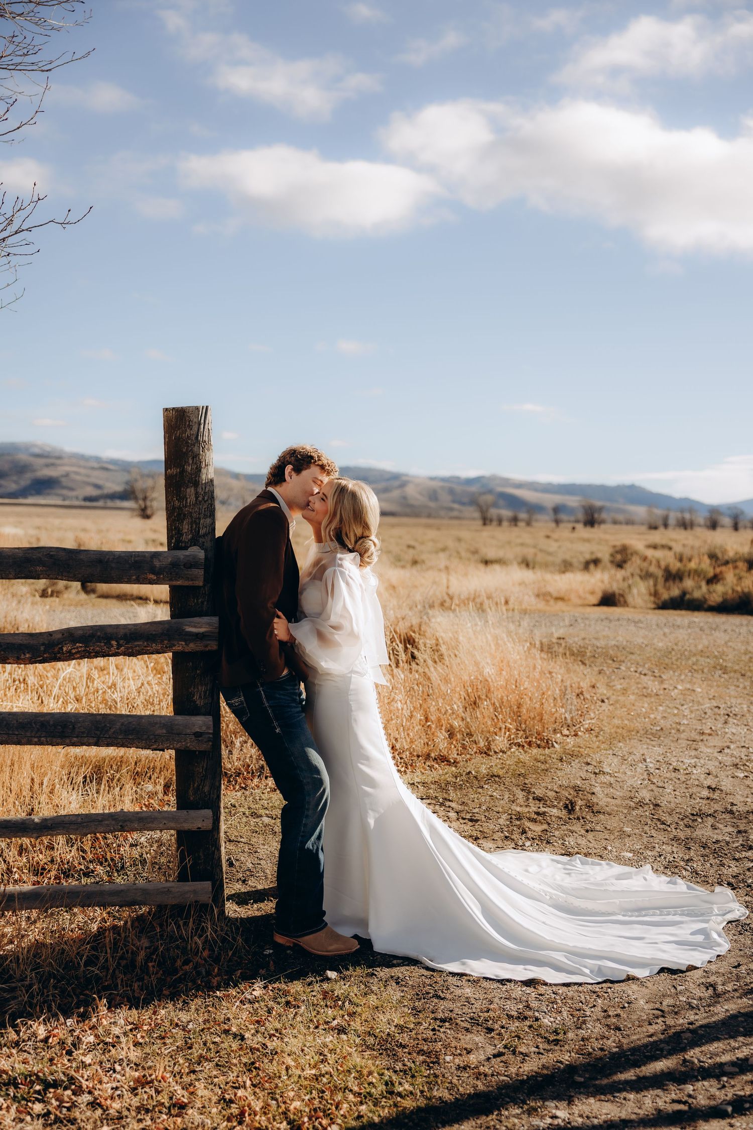 A romantic wedding photo series featuring a couple posing by a rustic wooden fence in a golden field.