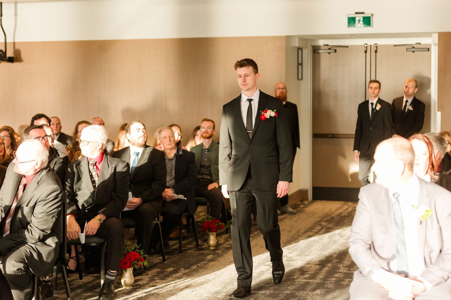 A wedding party walks down a hallway in a sequence of overlapping photos showing their movement and progression.