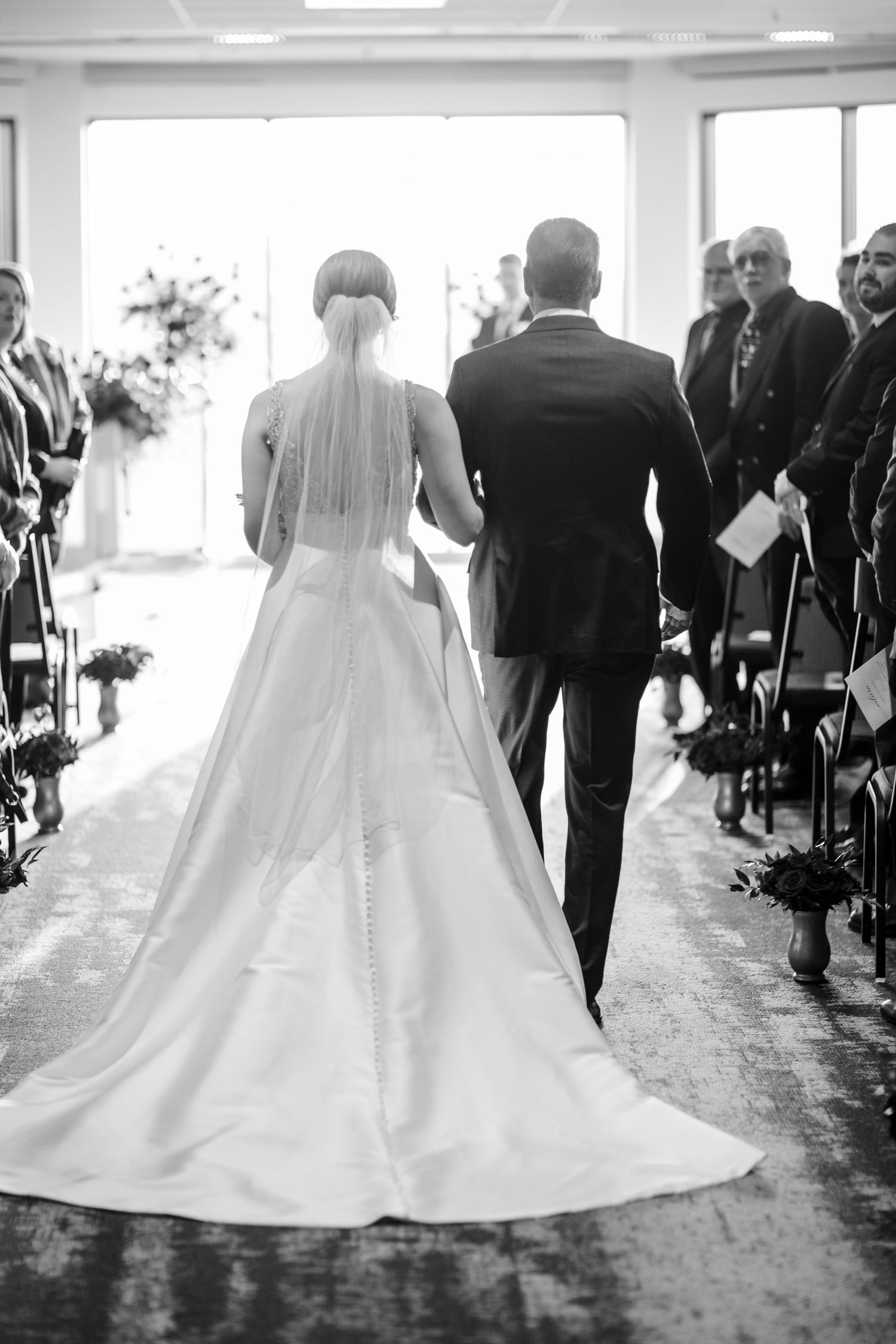 A sequence of black and white photos showing a bride in a ballgown walking down a church aisle during a wedding ceremony.