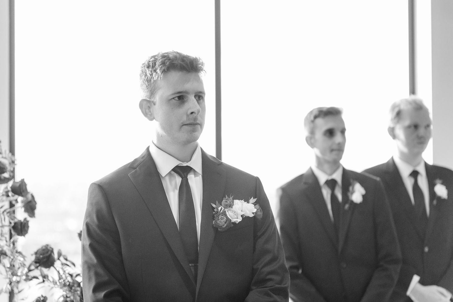 Wedding party members in black suits stand in a row during a formal ceremony.