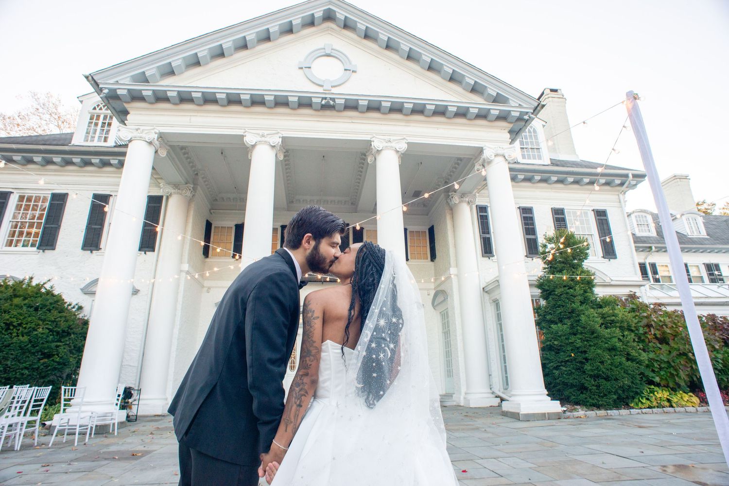A wedding couple stands in front of a grand white columned building during their special day.