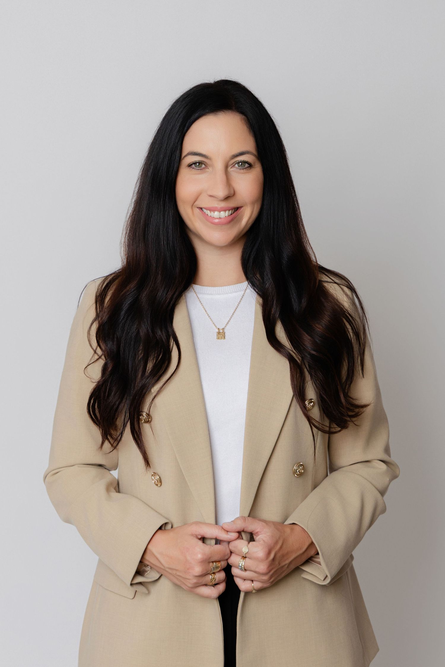 A person wearing a beige blazer and white top poses in a series of casual shots against a light background.