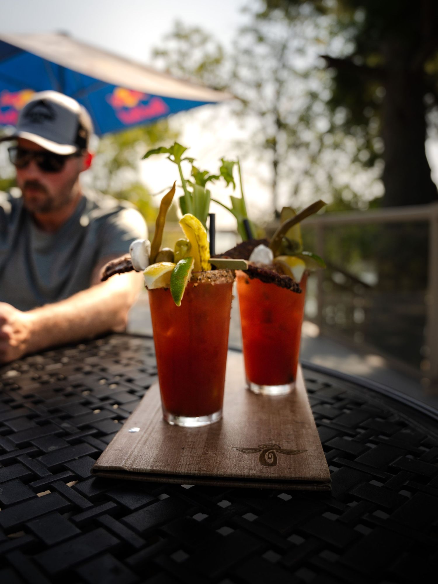 Bloody Mary cocktails garnished with celery on an outdoor patio table.