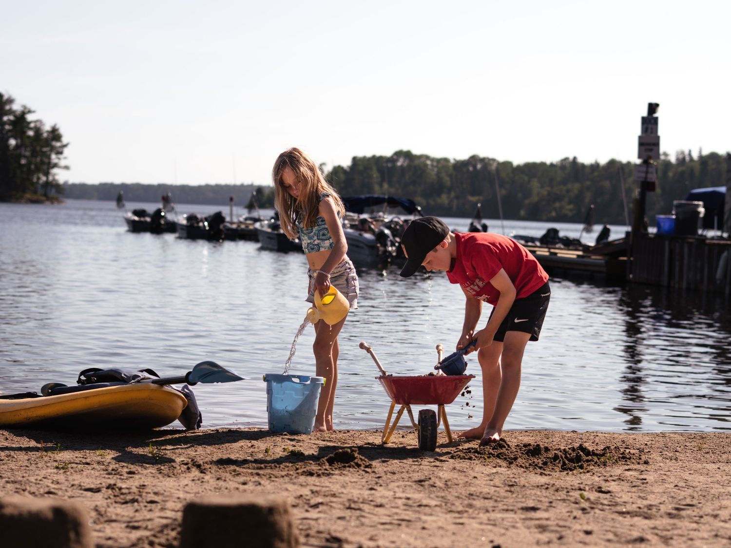 People enjoying recreational activities on a sandy beach near a lake.