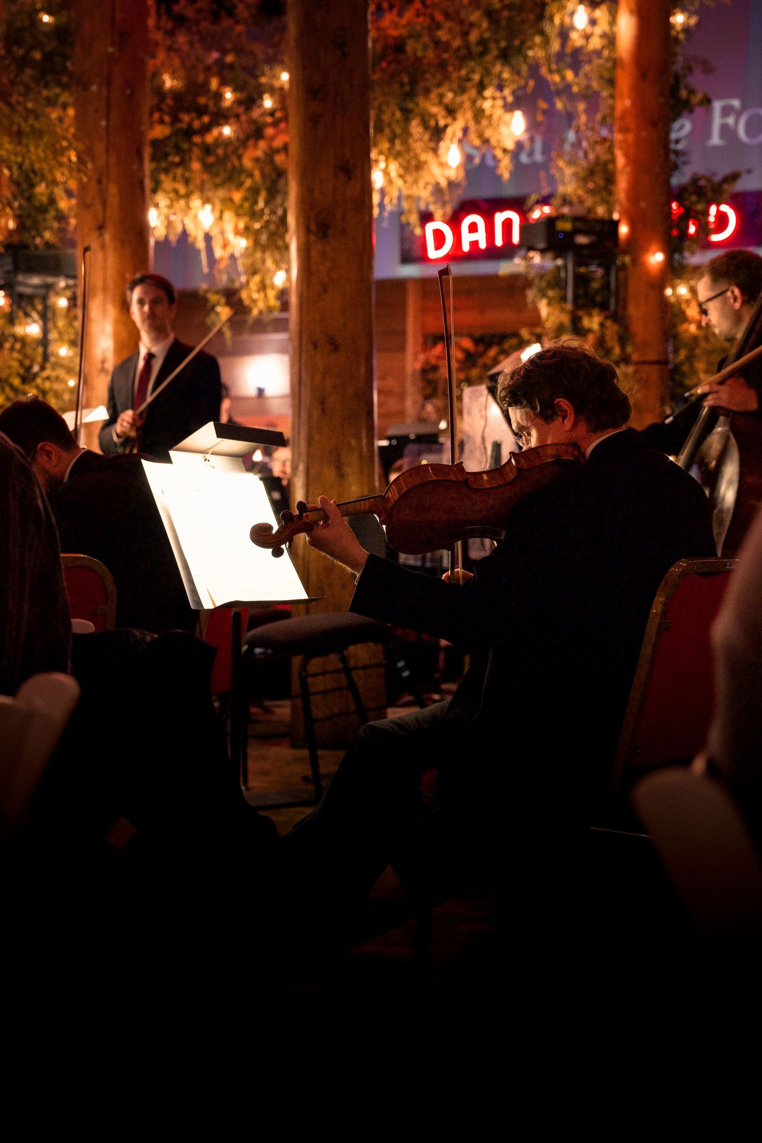 Musicians perform in silhouette under atmospheric lighting at an evening event.