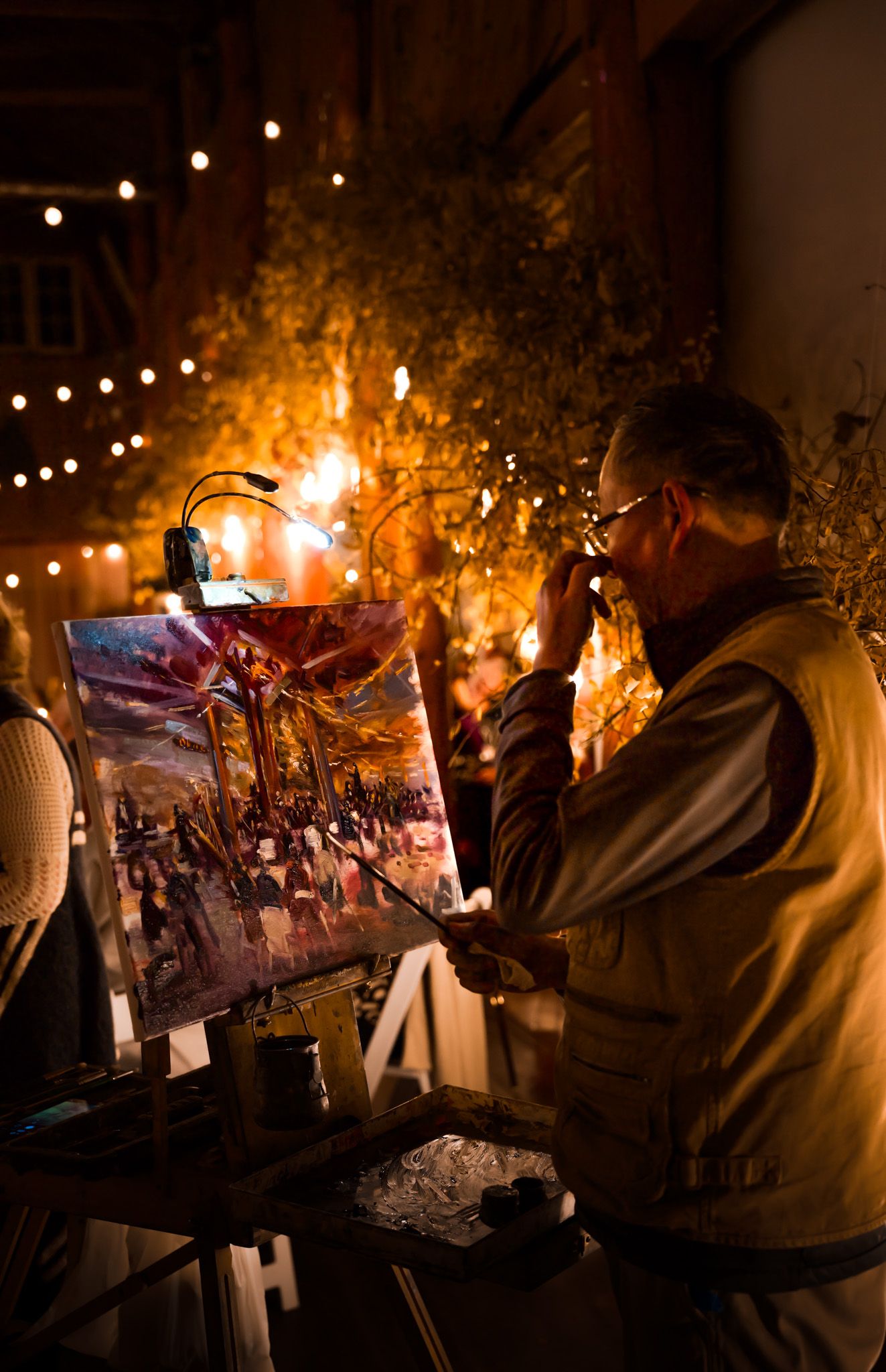 Artwork displays illuminated by string lights create an artistic nighttime gallery setting.