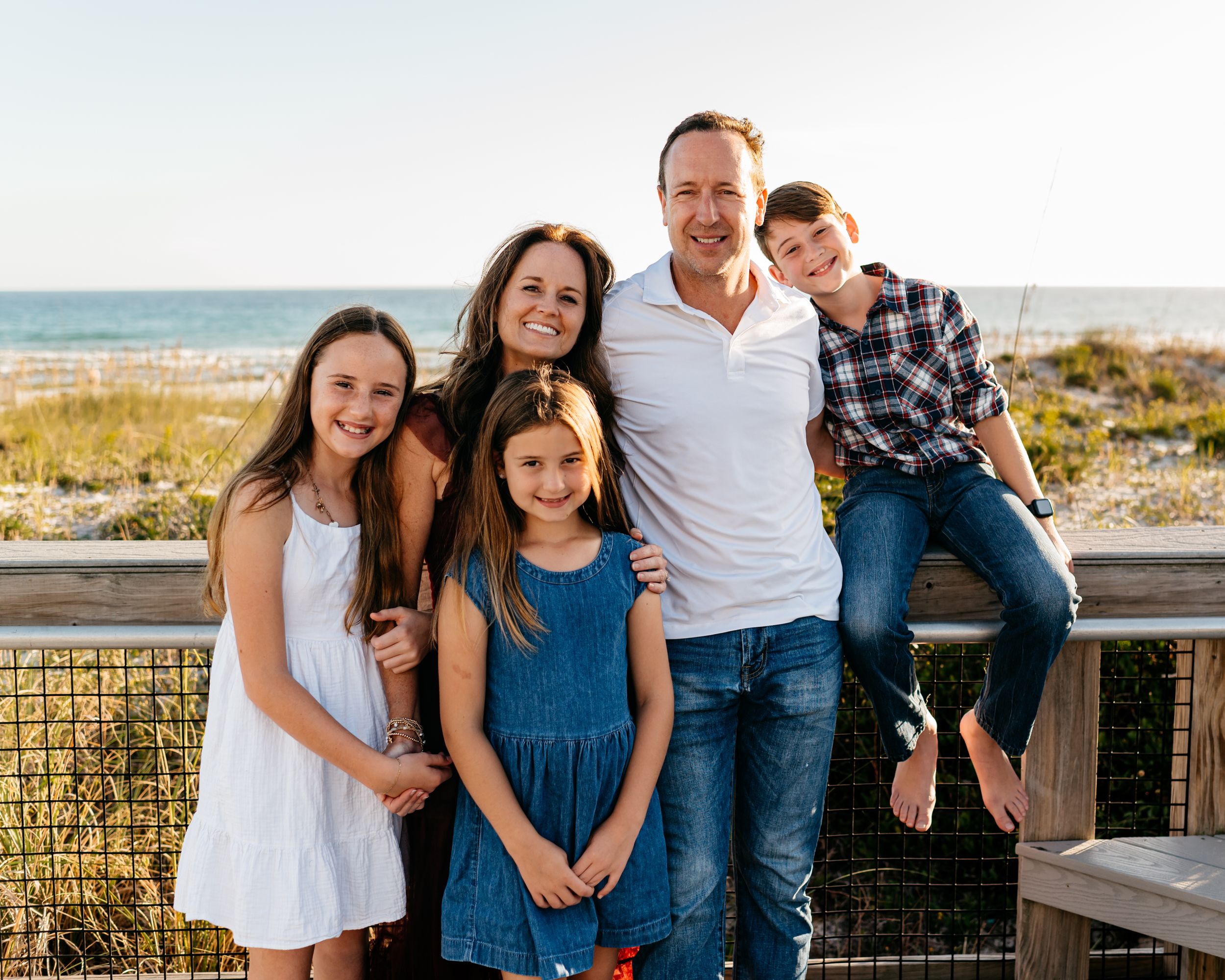 A series of casual outdoor family portraits taken at a beach boardwalk during golden hour.