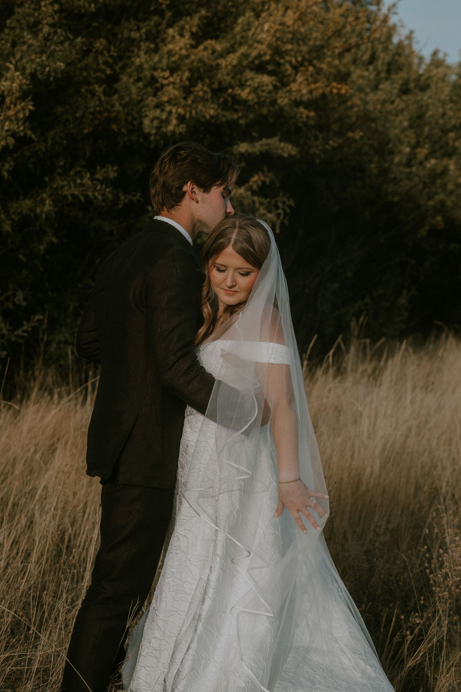 A romantic wedding couple shares an intimate moment against a backdrop of mountain forests on their special day.