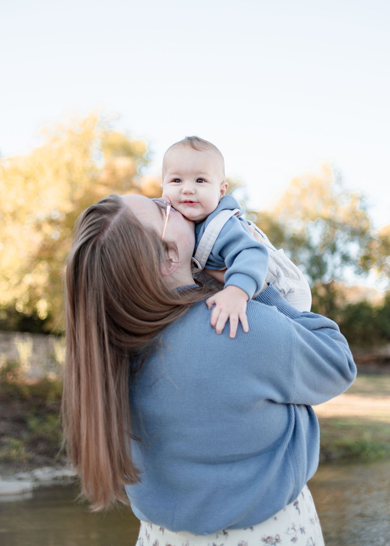 Mother kissing baby during outdoor family session at Nolan Creek in Belton Texas