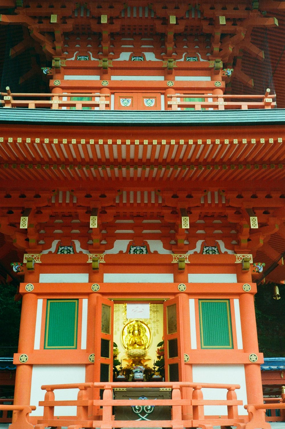 Traditional Japanese temple architecture features vibrant orange-red pagoda roofs with ornate green and gold details.