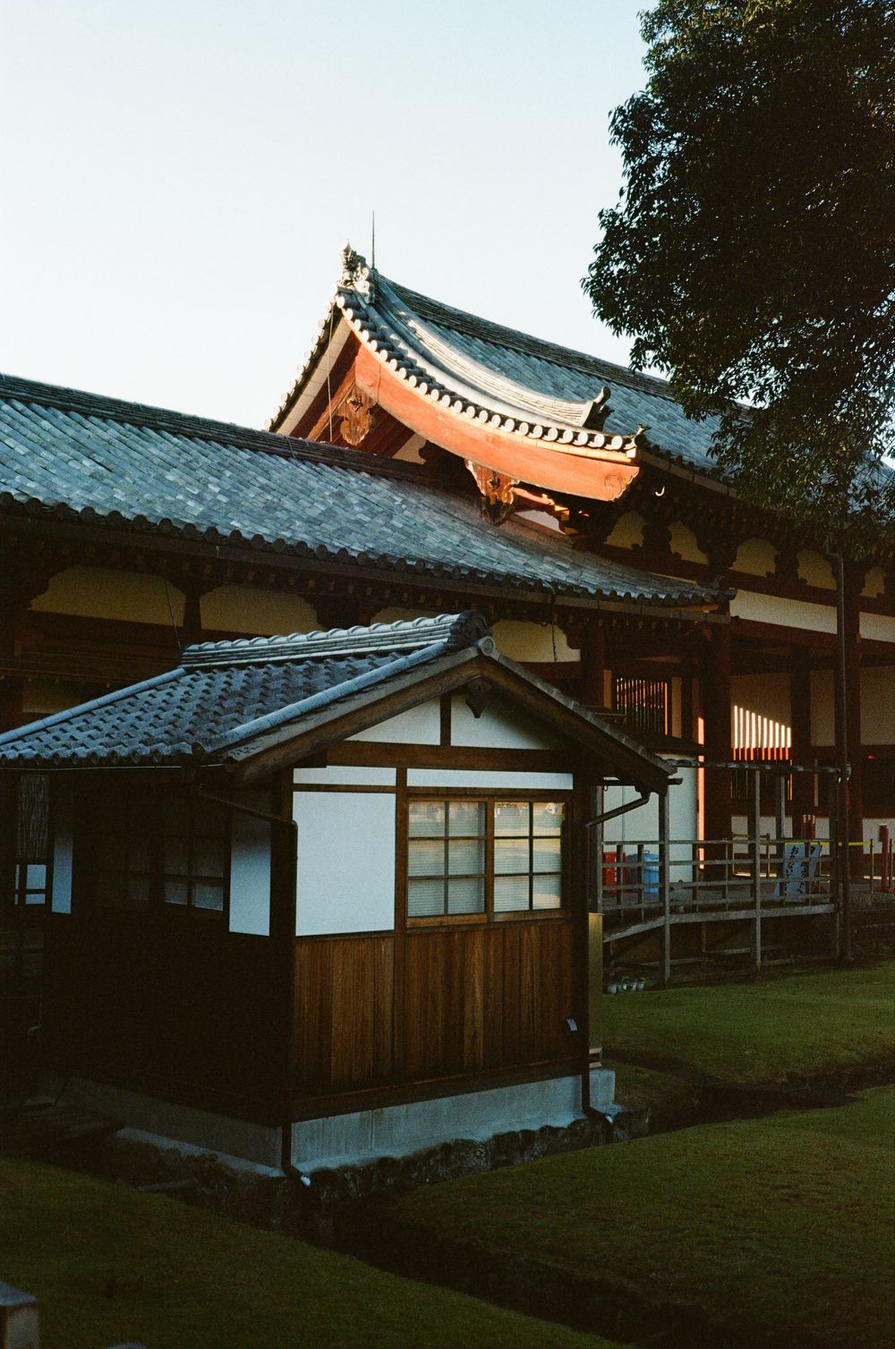 Traditional Japanese architecture with wooden buildings and blue-tiled roofs set against a serene natural landscape at dusk.