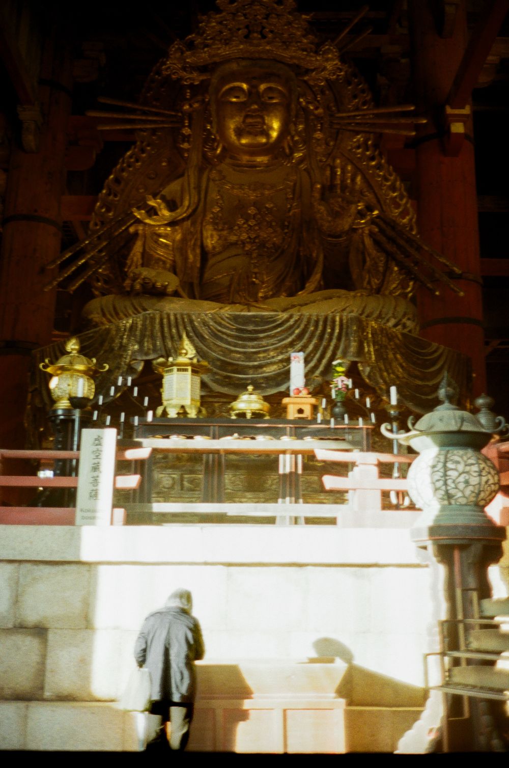 A panoramic view of ornate Buddhist temple decorations and statues illuminated by soft lighting.