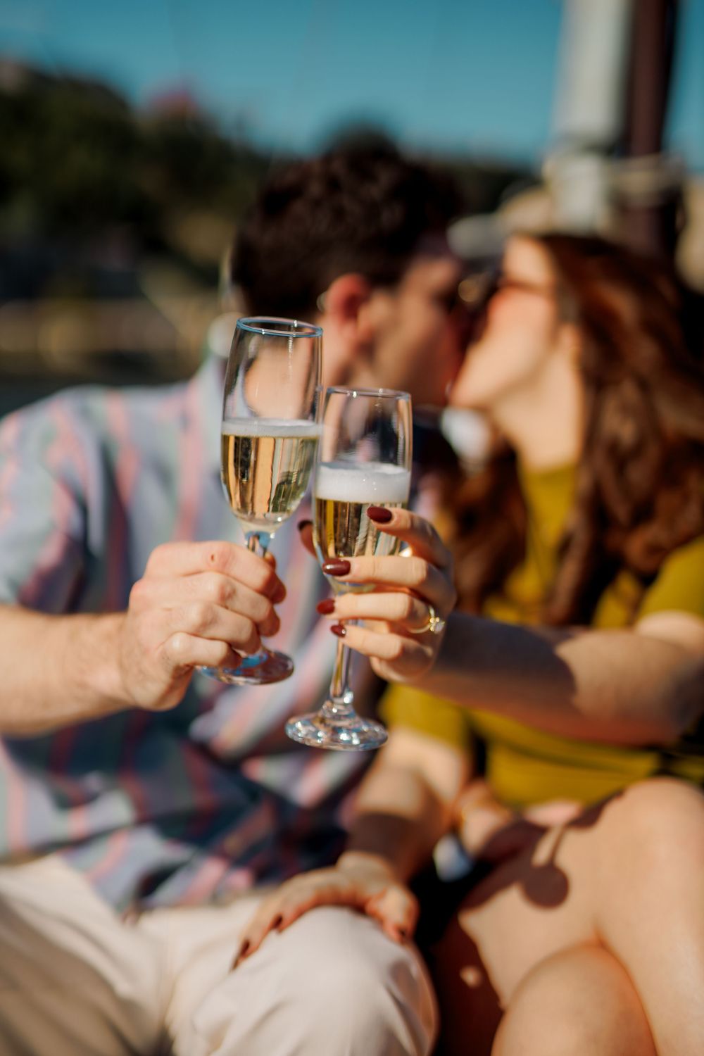 People toasting with champagne glasses at an outdoor gathering during golden hour.