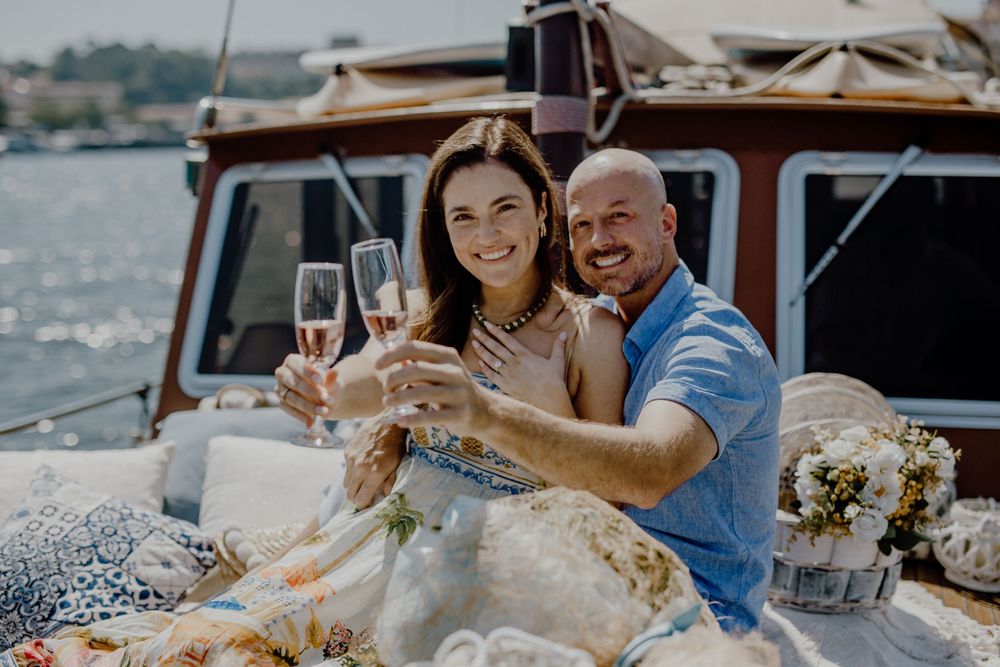 A couple enjoys champagne and snacks during a romantic boat date on a sunny afternoon.