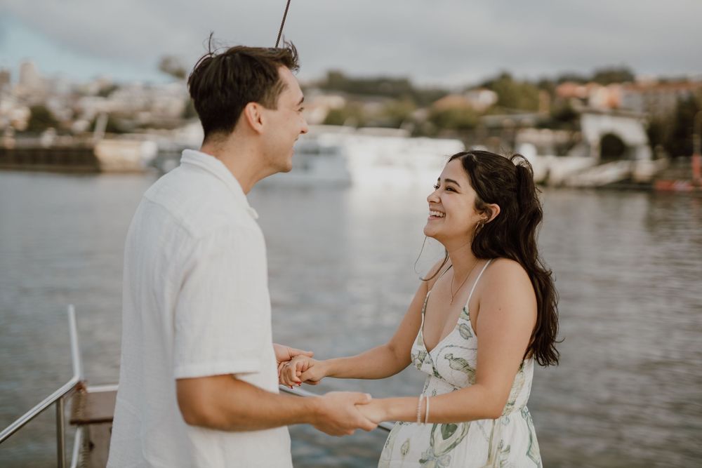 A couple shares a joyful moment together during a waterfront photo session at sunset.