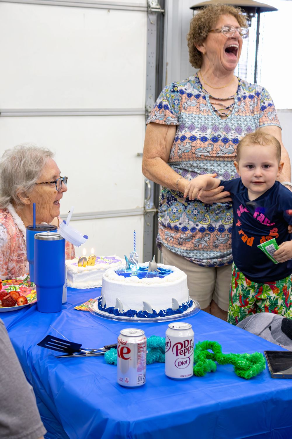 A blue tablecloth birthday celebration setup with a white frosted cake and party decorations.