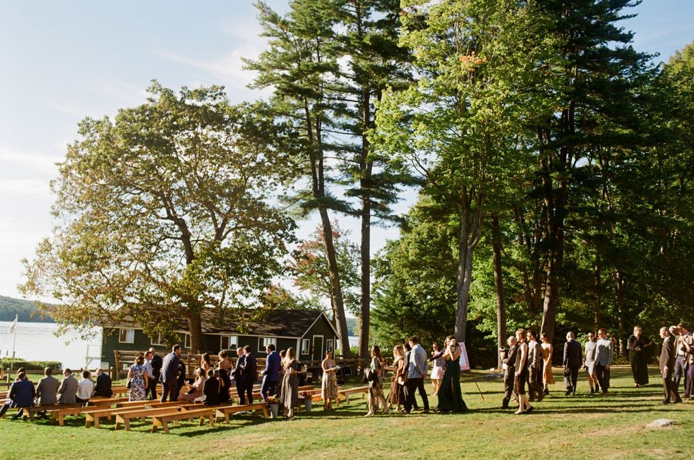 The wedding guests walk to the location of the ceremony and begin filling the aisles in anticipation of the ceremony on a summer's day.