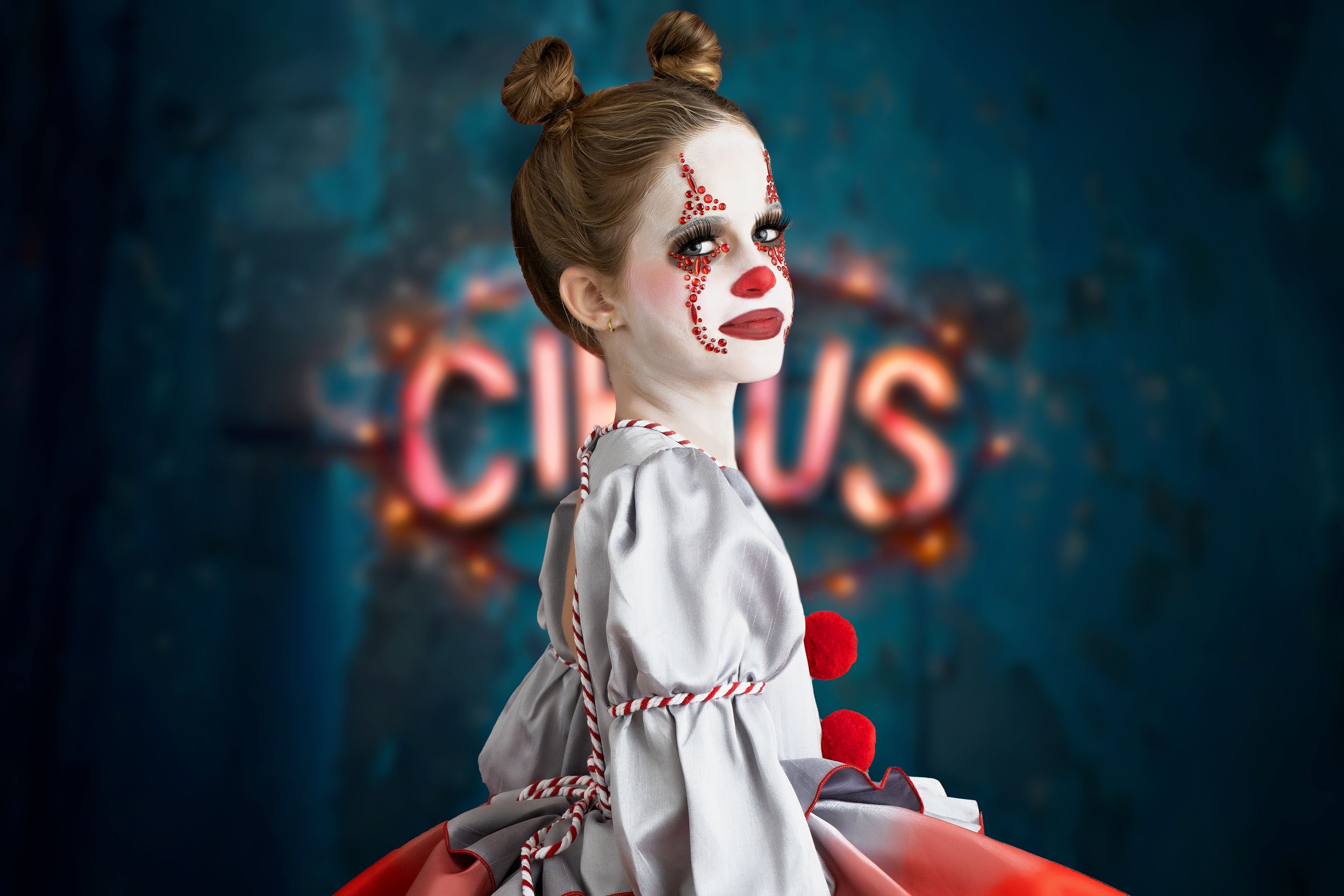 Girl dressed as Pennywise the clown standing in front of a blue and red circus sign