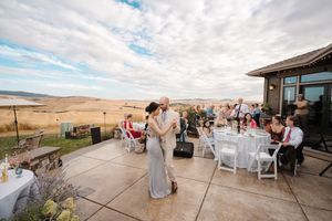 Panoramic view of an outdoor wedding reception venue with scenic mountain landscape and white chairs.