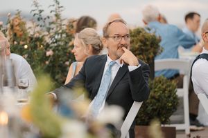 A guest sits thoughtfully at an outdoor wedding reception with garden decor and candlelight.