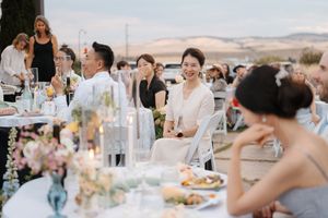 Guests raise glasses for toasts during sunset wedding reception with mountain backdrop.