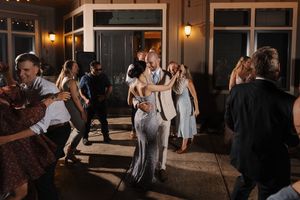 Wedding guests dancing and celebrating on a dimly lit dance floor during an evening reception.