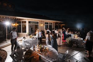 Wedding reception venue illuminated at night with string lights and dancing guests.