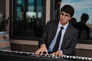 Professional pianist performing at an elegant event venue with dark lighting.