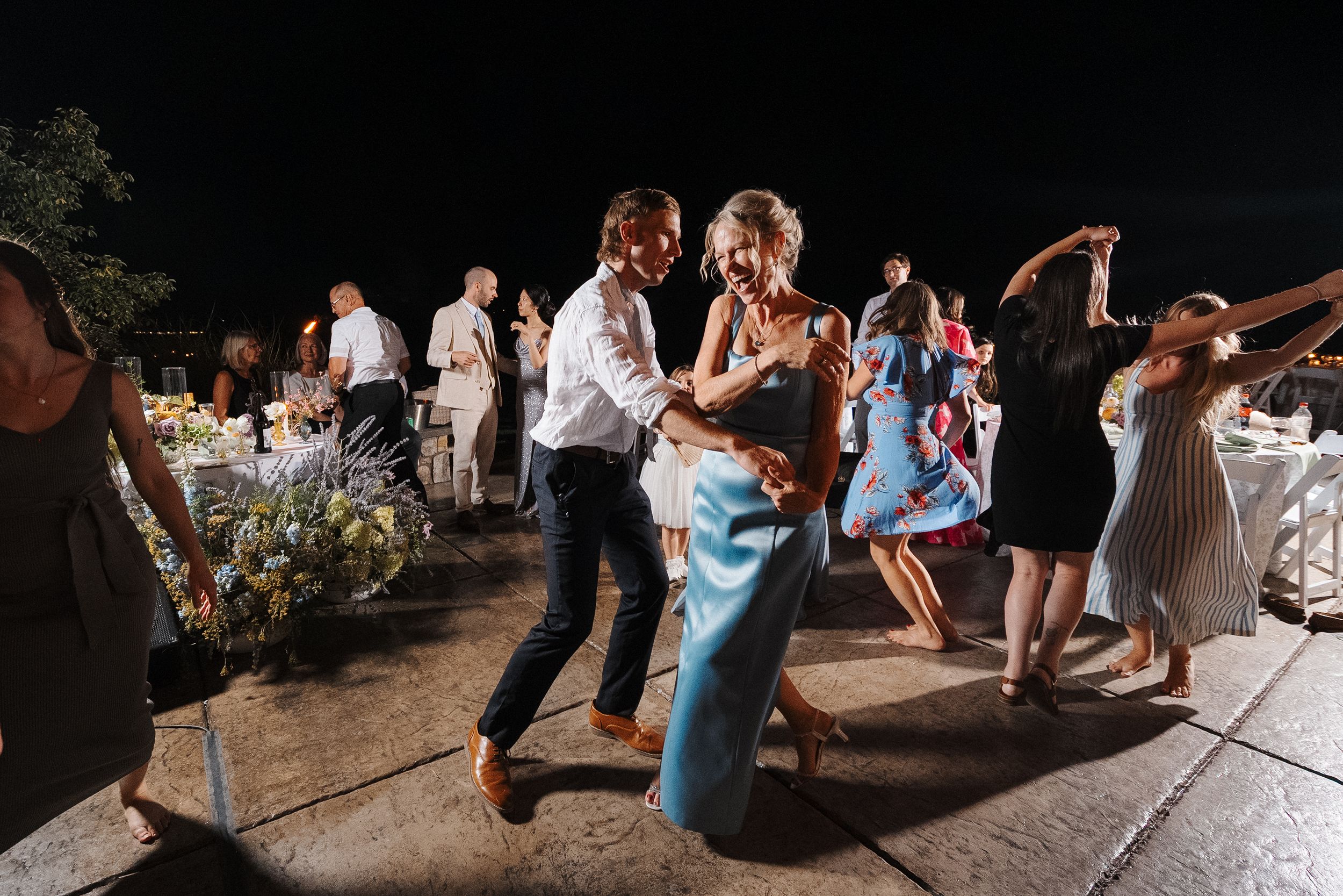 Guests dancing together on an outdoor dance floor at a wedding reception during evening celebrations.