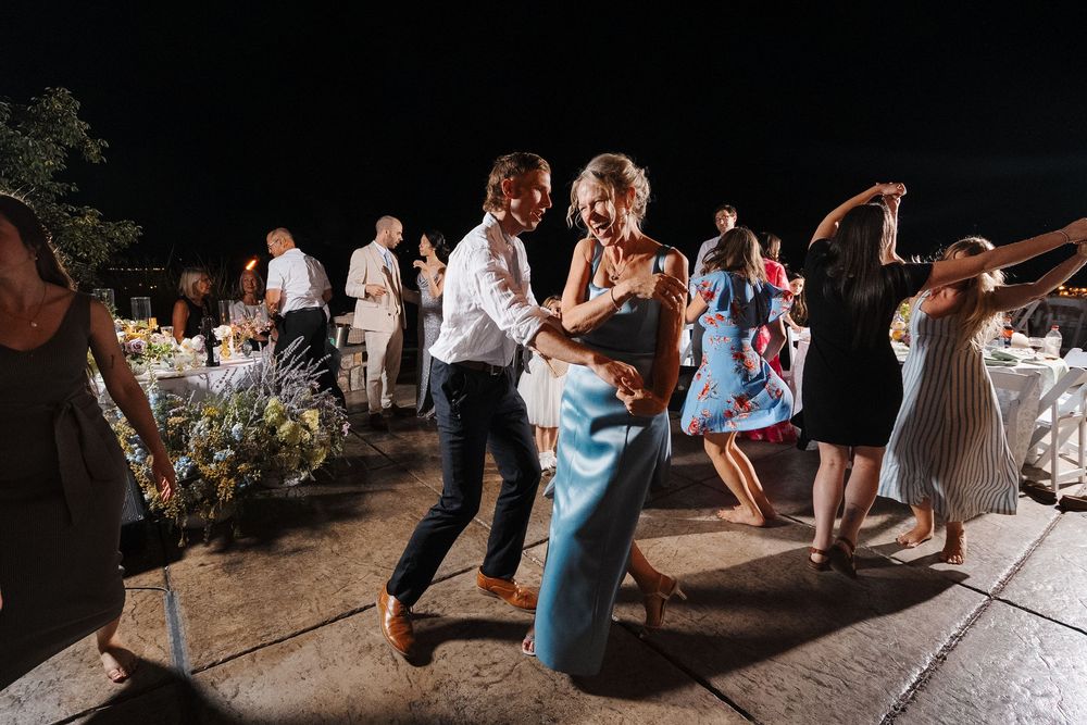 Guests dancing together on an outdoor dance floor at a wedding reception during evening celebrations.