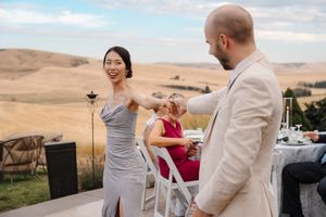 A couple celebrates their engagement at sunset in a scenic vineyard setting with rolling hills in the background.