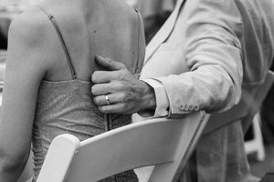 Close-up details of formal attire and linked arms at an elegant wedding reception.