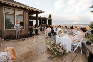 Outdoor wedding reception on a patio with mountain views and elegant table settings at sunset.