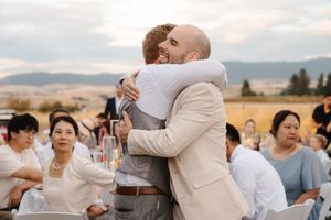 Emotional embraces and hugs shared between guests during outdoor wedding celebration.