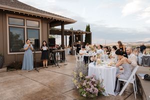 Wedding reception guests enjoying cocktail hour on an outdoor patio with mountain views at sunset.