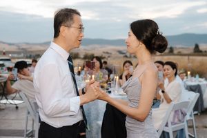 Guests dancing and conversing at an outdoor wedding reception with mountain scenery.