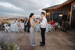 Wedding guests mingle on a spacious outdoor venue patio at sunset with mountain views in the background.