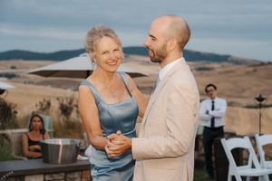 Couple dances together during an outdoor celebration with rolling hills in the background.