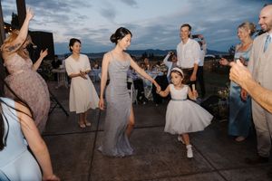 Wedding guests dance and celebrate on an outdoor patio during sunset reception festivities.