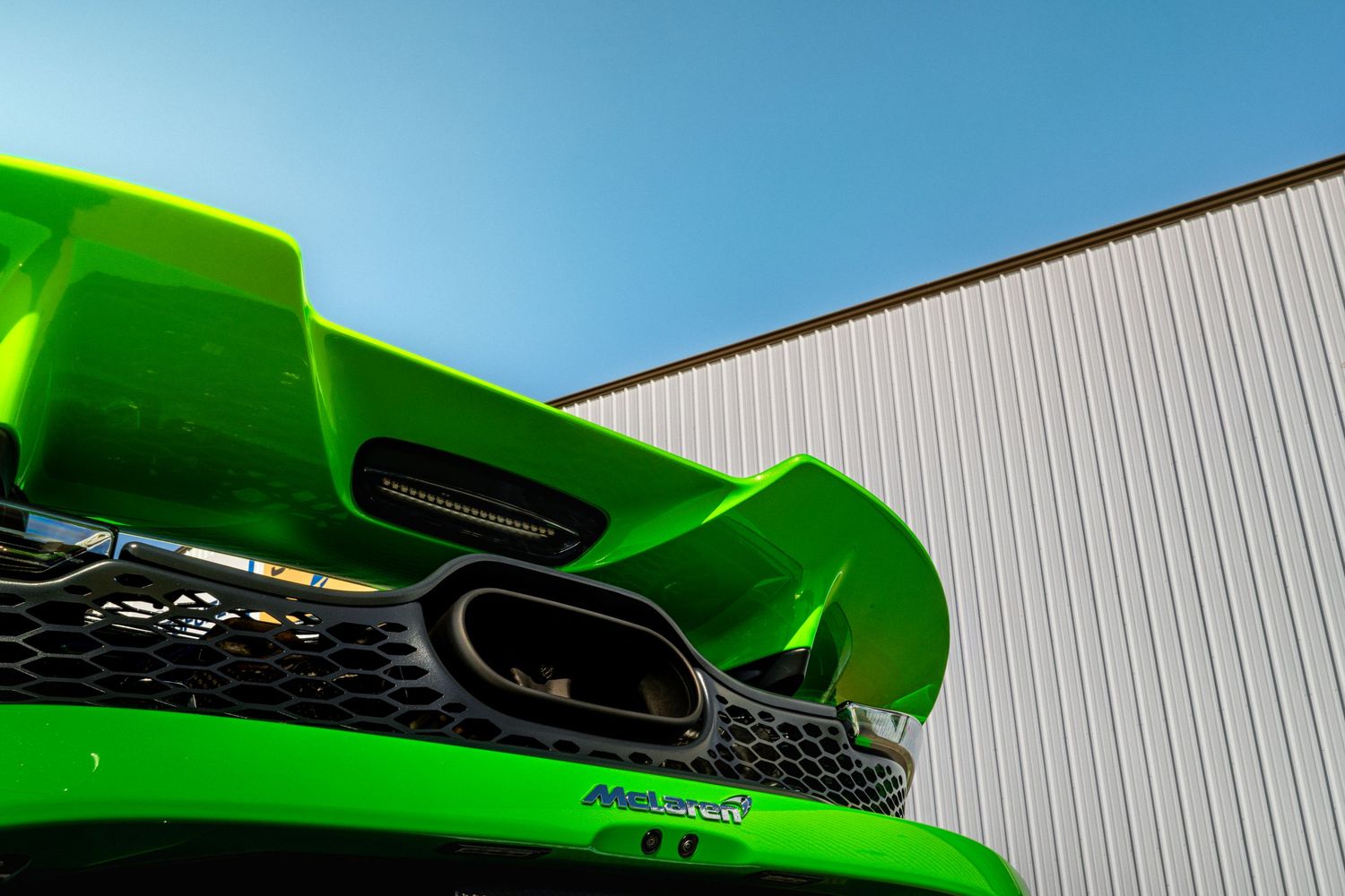 A bright green Lamborghini Huracan sports car is shown from multiple angles against a white industrial building.