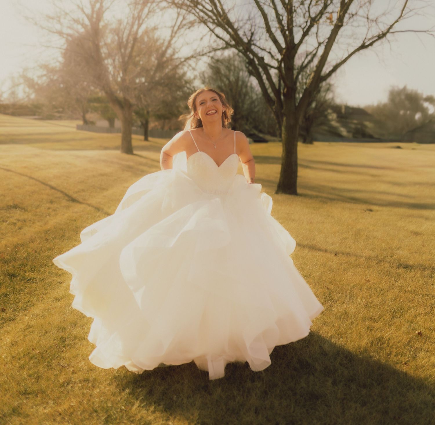 Cherry blossom trees frame a white wedding dress hanging ethereally in a spring garden setting.