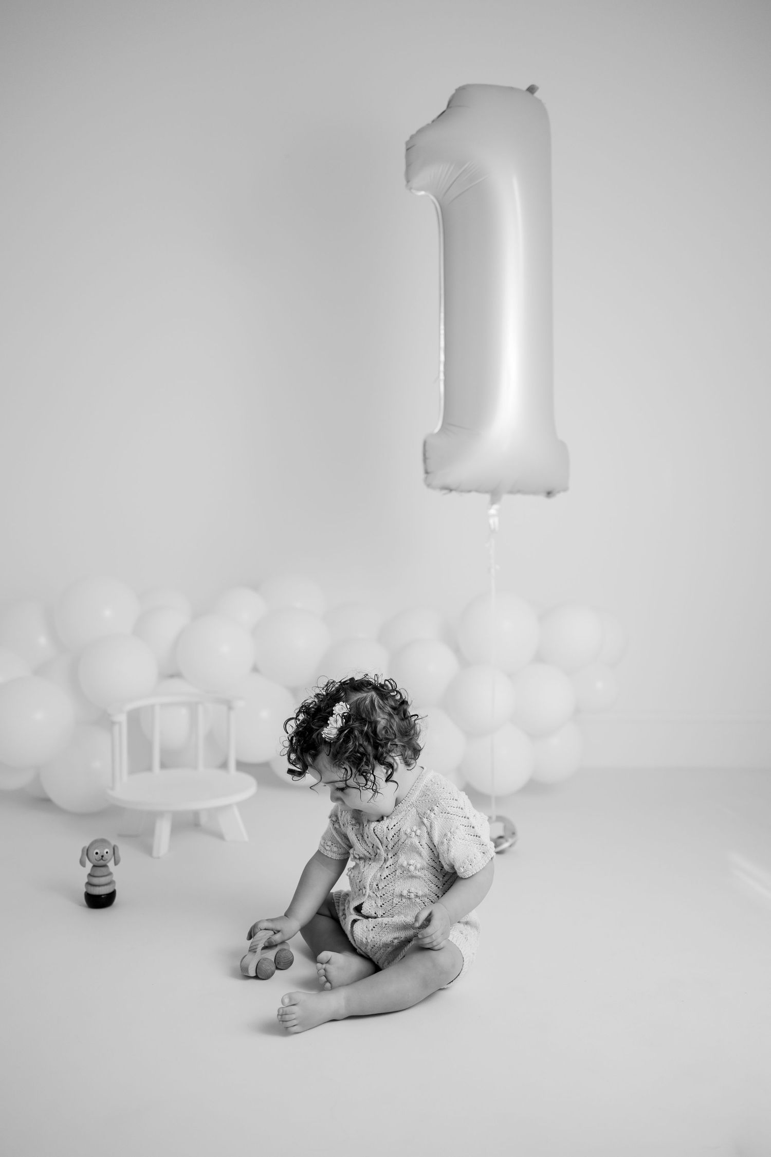 A baby plays and splashes in a bubble bath while looking up with joy in a black and white photo series.