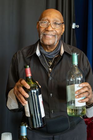 A smiling senior wearing glasses and a black jacket holds up various wine bottles in a sequence of photos.