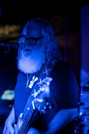 A series of blue-lit concert photos showing a performer singing into a microphone in dark lighting.