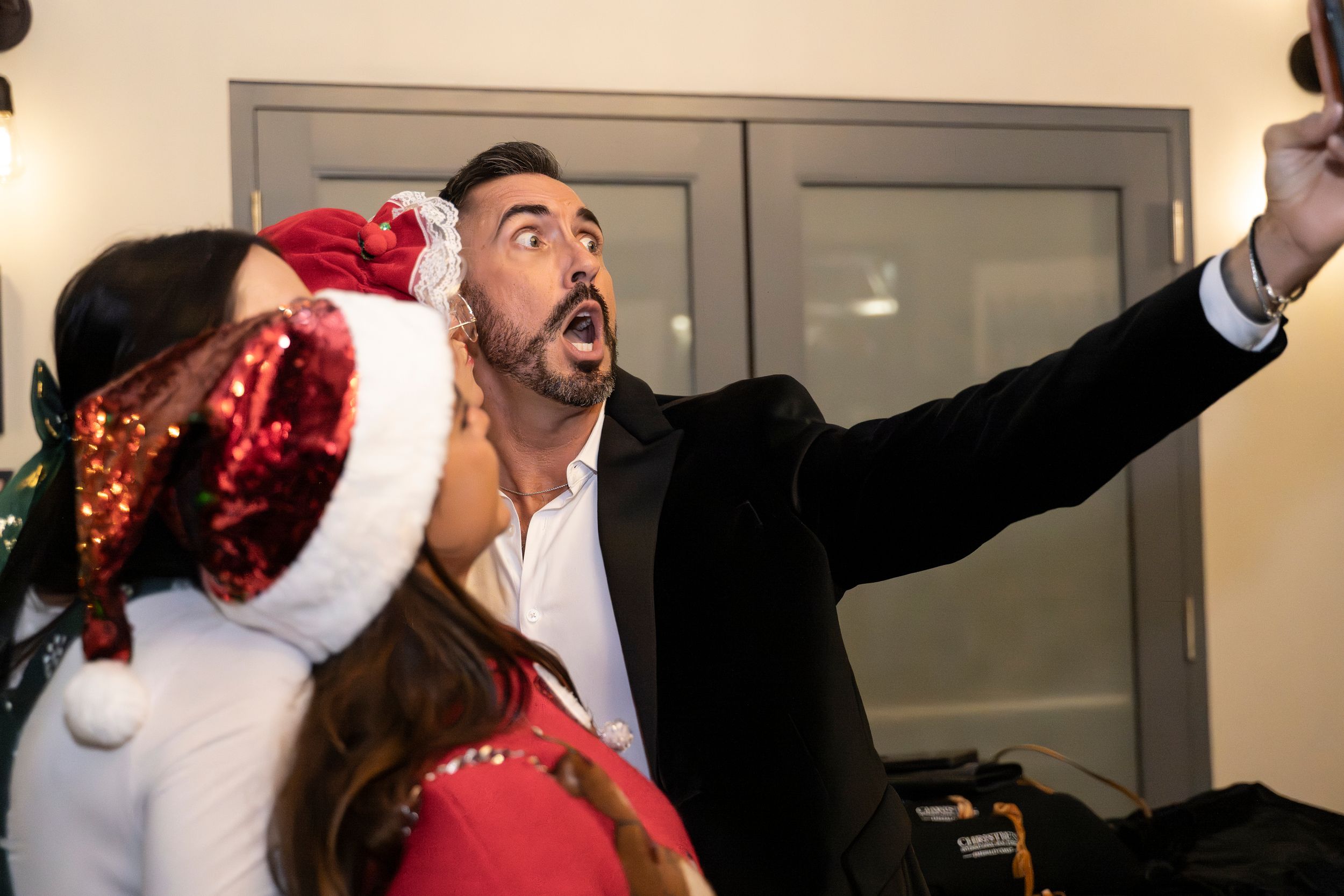 A collage of people wearing Santa hats and holiday attire posing playfully in an office setting.