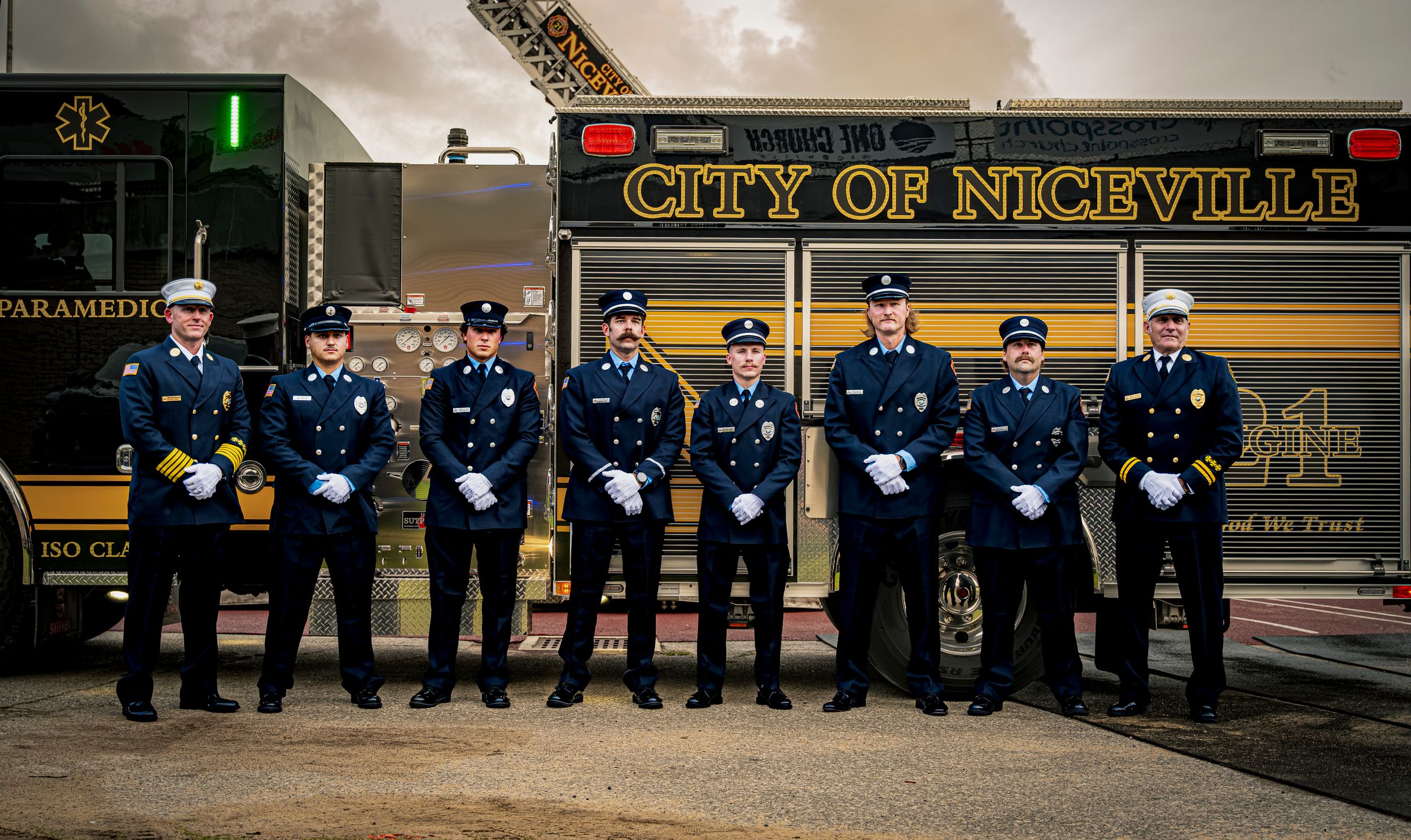 City of Niceville firefighters and paramedics in dress uniforms pose proudly in front of a fire truck.