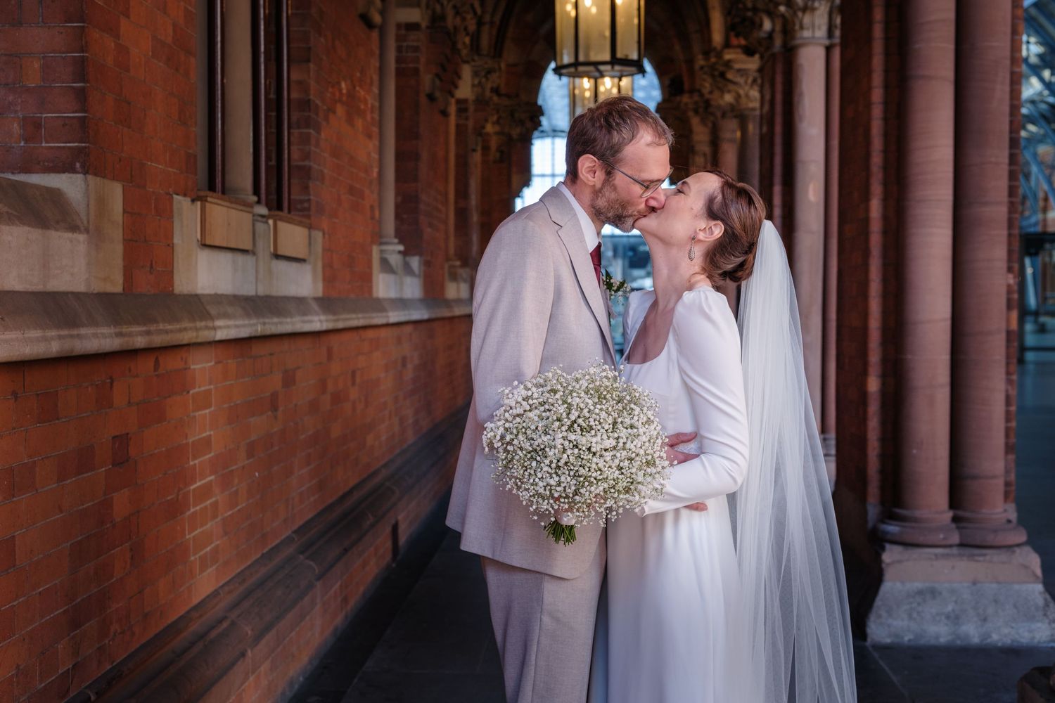 A romantic wedding moment captured in front of a historic brick church with ornate architecture.