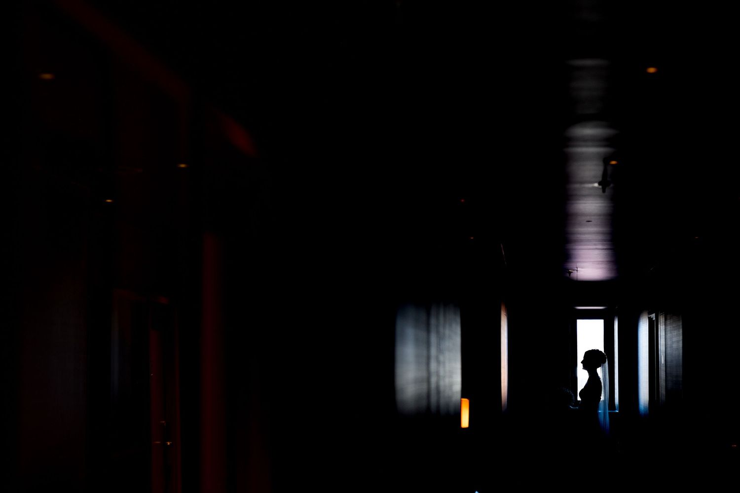 Dark corridor with dramatic lighting and silhouettes creates an eerie atmosphere in abandoned building interior.