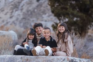A family group poses together outdoors on a winter day wearing coordinated neutral colored outfits.