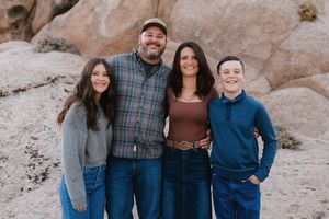 Family group poses together against desert rock formation backdrop.